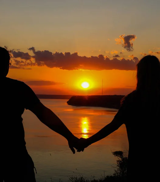 Sahilde el ele tutuşan romantik çiftin silueti ve deniz üzerinde gün batımını izlemek, aşk ve tatil konsepti, sıcak yaz, arkadan manzara. — Stok fotoğraf