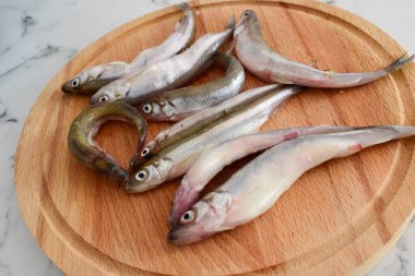 Ahşap bir tahtada, küçük bir nehir balığının üzerinde eriyordu.