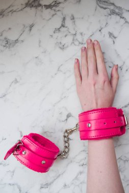 Erotik oyunlar için pembe kelepçeler. Kadın eli, kürklü kelepçe takıyor.