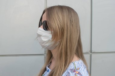 Uzun kahverengi saçlı kadın, tıbbi maske ve güneş gözlüğü.