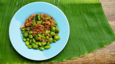  Kızarmış domuz pirzolası ve muz yaprağında mavi tabakta fasulye.