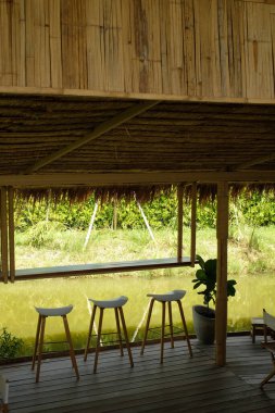 Göletin kenarında, tahta zeminde üç sandalye.