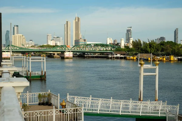 White piers by a river with a bridge and buildings on backdrop 2