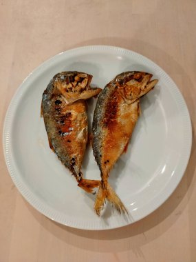  Beyaz tabakta iki kızarmış uskumru.