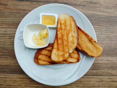 Tereyağlı tost ve beyaz tabakta reçel.