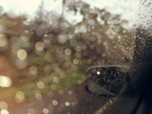 Blurred image, Rain drops on the car glass window with road in rainy season abstract background, water drop on the glass, night storm raining car driving concept