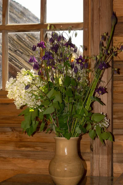 Ein Strauß Gartenblumen vor einer Holzwand in einem Tontopf — Stockfoto