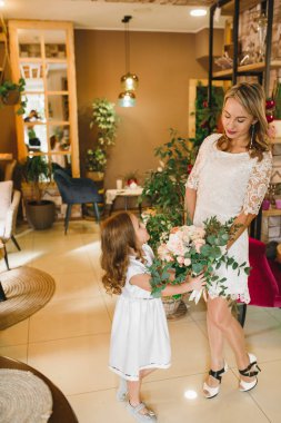 Anne ve kızı caffe çiçeklerle. Evlat annesine çiçek ver. sevimli bir aile. Dünya Kadınlar günü 8 Mart kutluyor