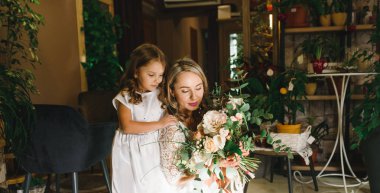 Anne ve kızı caffe çiçeklerle. Evlat annesine çiçek ver. sevimli bir aile. Dünya Kadınlar günü 8 Mart kutluyor