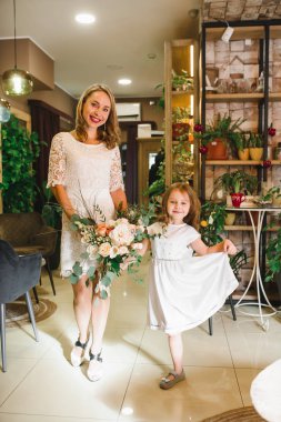 Anne ve kızı caffe çiçeklerle. Evlat annesine çiçek ver. sevimli bir aile. Dünya Kadınlar günü 8 Mart kutluyor