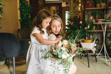 Anne ve kızı caffe çiçeklerle. Evlat annesine çiçek ver. sevimli bir aile. Dünya Kadınlar günü 8 Mart kutluyor