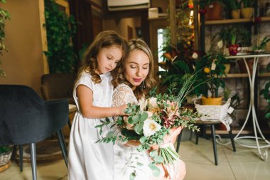 Anne ve kızı caffe çiçeklerle. Evlat annesine çiçek ver. sevimli bir aile. Dünya Kadınlar günü 8 Mart kutluyor