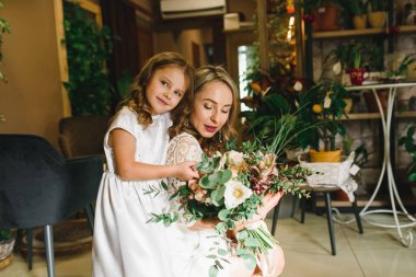 Anne ve kızı caffe çiçeklerle. Evlat annesine çiçek ver. sevimli bir aile. Dünya Kadınlar günü 8 Mart kutluyor