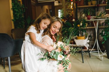 Anne ve kızı caffe çiçeklerle. Evlat annesine çiçek ver. sevimli bir aile. Dünya Kadınlar günü 8 Mart kutluyor