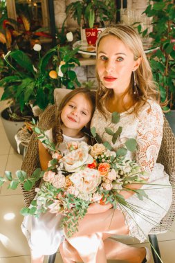 Anne ve kızı caffe çiçeklerle. Evlat annesine çiçek ver. sevimli bir aile. Dünya Kadınlar günü 8 Mart kutluyor