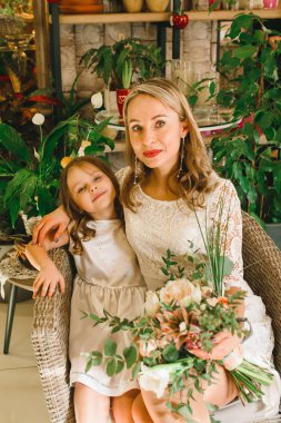 Anne ve kızı caffe çiçeklerle. Evlat annesine çiçek ver. sevimli bir aile. Dünya Kadınlar günü 8 Mart kutluyor