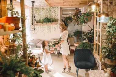 Anne ve kızı caffe çiçeklerle. Evlat annesine çiçek ver. sevimli bir aile. Dünya Kadınlar günü 8 Mart kutluyor