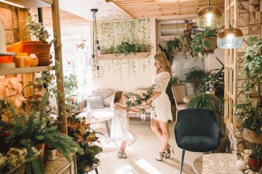 Anne ve kızı caffe çiçeklerle. Evlat annesine çiçek ver. sevimli bir aile. Dünya Kadınlar günü 8 Mart kutluyor