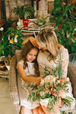 Anne ve kızı caffe çiçeklerle. Evlat annesine çiçek ver. sevimli bir aile. Dünya Kadınlar günü 8 Mart kutluyor