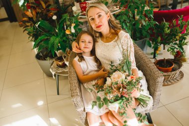 Anne ve kızı caffe çiçeklerle. Evlat annesine çiçek ver. sevimli bir aile. Dünya Kadınlar günü 8 Mart kutluyor