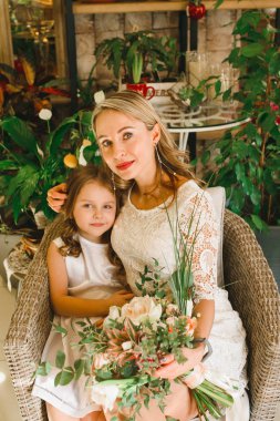 Anne ve kızı caffe çiçeklerle. Evlat annesine çiçek ver. sevimli bir aile. Dünya Kadınlar günü 8 Mart kutluyor