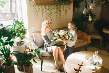 Anne ve kızı caffe çiçeklerle. Evlat annesine çiçek ver. sevimli bir aile. Dünya Kadınlar günü 8 Mart kutluyor