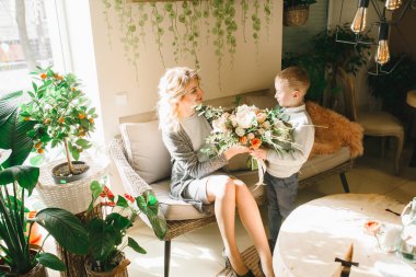 Anne ve kızı caffe çiçeklerle. Evlat annesine çiçek ver. sevimli bir aile. Dünya Kadınlar günü 8 Mart kutluyor