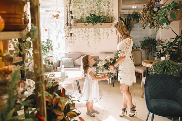 Anne ve kızı caffe çiçeklerle. Evlat annesine çiçek ver. sevimli bir aile. Dünya Kadınlar günü 8 Mart kutluyor