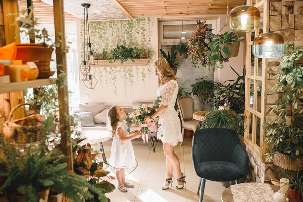 Anne ve kızı caffe çiçeklerle. Evlat annesine çiçek ver. sevimli bir aile. Dünya Kadınlar günü 8 Mart kutluyor