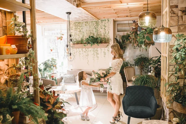 Anne ve kızı caffe çiçeklerle. Evlat annesine çiçek ver. sevimli bir aile. Dünya Kadınlar günü 8 Mart kutluyor