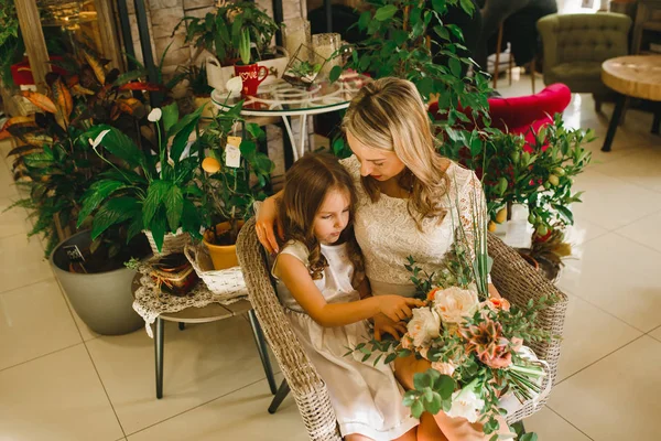 Mom and daughter with flowers in caffe. Son give flowers to mother. cute family. International women`s day, 8 march celebrating