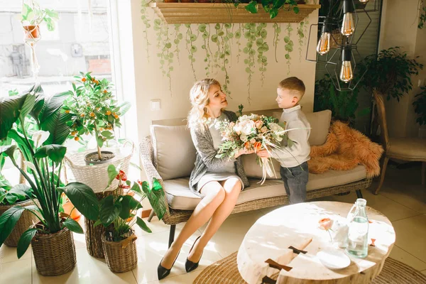 Anne ve kızı caffe çiçeklerle. Evlat annesine çiçek ver. sevimli bir aile. Dünya Kadınlar günü 8 Mart kutluyor