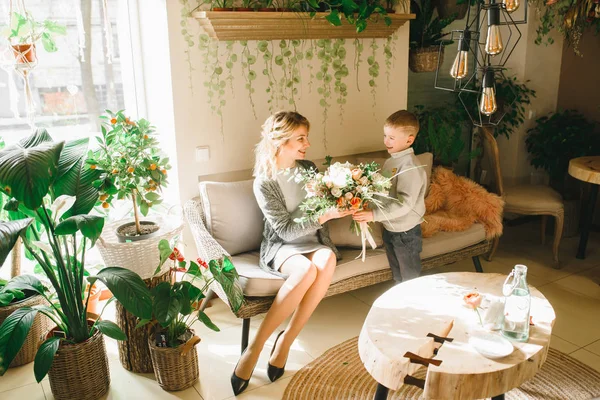 Anne ve kızı caffe çiçeklerle. Evlat annesine çiçek ver. sevimli bir aile. Dünya Kadınlar günü 8 Mart kutluyor