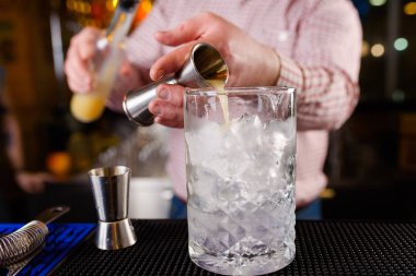 Uzman barmen gece kulübünde kokteyl yapıyor, barmen bir kokteyl elinde tutuyor. Yüzü yok. Seçici odak