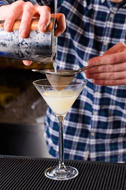 Uzman barmen gece kulübünde kokteyl yapıyor, barmen bir kokteyl elinde tutuyor. Yüzü yok. Seçici odak