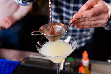 Uzman barmen gece kulübünde kokteyl yapıyor, barmen bir kokteyl elinde tutuyor. Yüzü yok. Seçici odak