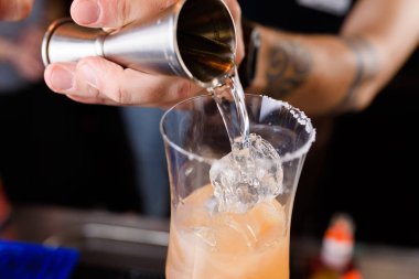 Uzman barmen gece kulübünde kokteyl yapıyor, barmen bir kokteyl elinde tutuyor. Yüzü yok. Seçici odak