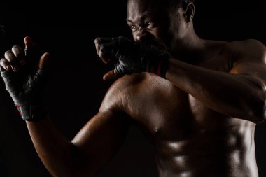 Siyah arka planda atletik Afrikalı dövüşçü. Koyu tenli, çıplak bir adam kavga ediyor. Spor kulübü ve spor salonuna yönlendir. Profesyonel boks ve karate