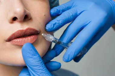 Çekici bir kız için dudak büyütme iğneleri. Estetik cerrah tıbbi klinikte dudağına iğne yapar. Kozmetik yenileme yüz tedavisi. Reklam için boş alan