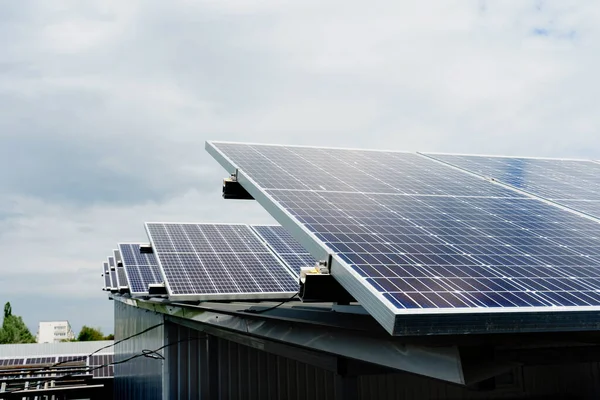 Solar panels stands in row on the roof . Free electricity for home. Sustainability of planet. Green energy. Solar cells power plant business. Ecological clean energy. Blue panels on the ground.