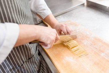 Mutfakta erişte kes. Şef restoranda spagetti pişiriyor. Şef bıçakla doğranır. Un ile işlenmemiş erişte.