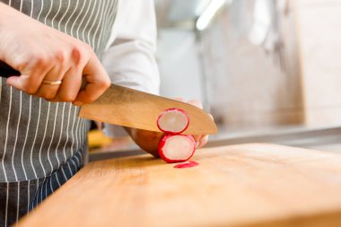 Mutfakta turp çorbası kes. Şef restoranda bıçakla turp pişirir. Kesme tahtasında turp