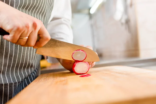 Cut radish for ramen soup on kitchen . Chef cooks radish with knife in restaurant. Radish on cutting board