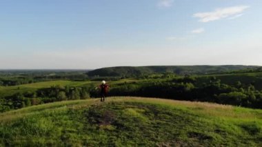Gürcü kız, beyaz papakha ve kırmızı ulusal elbisesiyle İHA 'dan ulusal dans ediyor. Dans adı: rachuli, acharuli, osuri, shalaxo, mtiuluri. Yeşil tepelerde. Gürcistan kültür yaşam tarzı.