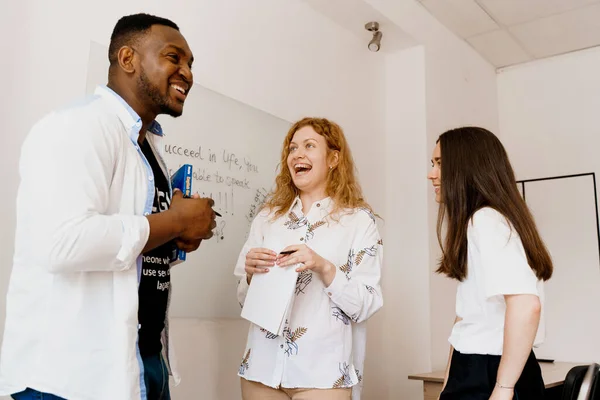 Multiethnic happy students and black teacher study foreign languages and smile and laught together in class. Studing with laptop. Black handsome student study with white people together.