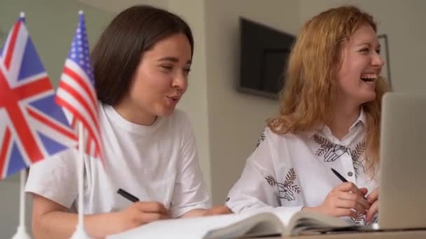 外国の学校の私立研究 女の子と笑った 先生はノートパソコンを使って母国語の文法を説明する 家庭教師による試験の準備 前に英語とイギリスの旗 — ストック動画