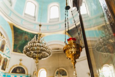 Kilisede kırmızı şamdanlı altın sarısı. Arka planda büyük bir avize var. Kilise içi.