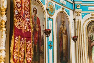 Kilisenin arka bahçesinde kırmızı şamdanlı altın sansürcüler. Kilise içi.