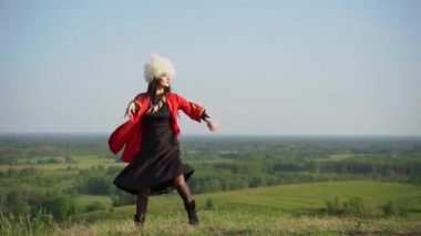 Beyaz papakha ve kırmızı ulusal elbise giymiş Gürcü kız ulusal dans dansı yapıyor: rachuli, acharuli, osuri, shalaxo, mtiuluri. Gürcistan 'ın yeşil tepelerinde. Gürcistan kültür yaşam tarzı.
