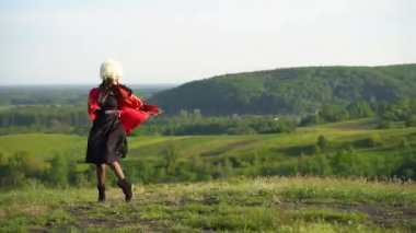 Beyaz papakha ve kırmızı ulusal elbise giymiş Gürcü kız ulusal dans dansı yapıyor: rachuli, acharuli, osuri, shalaxo, mtiuluri. Gürcistan 'ın yeşil tepelerinde. Gürcistan kültür yaşam tarzı.